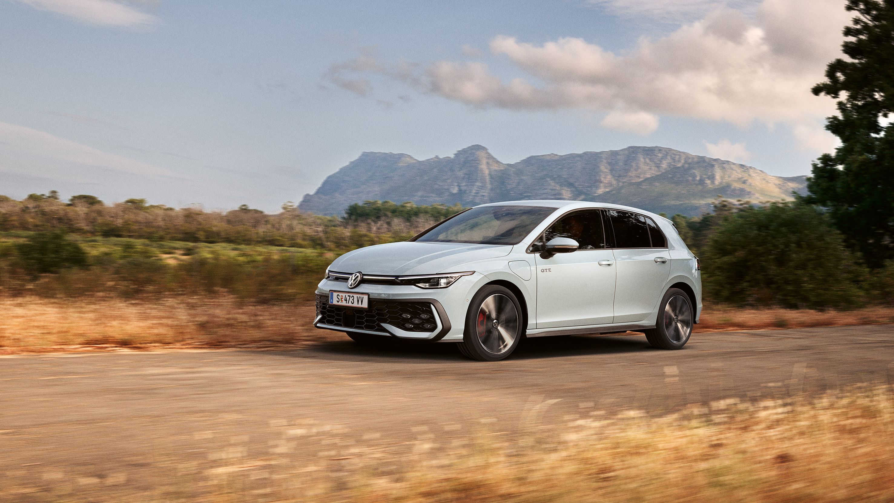 Der VW Golf GTE fährt auf einer Landstraße, im Hintergrund sieht man Berge