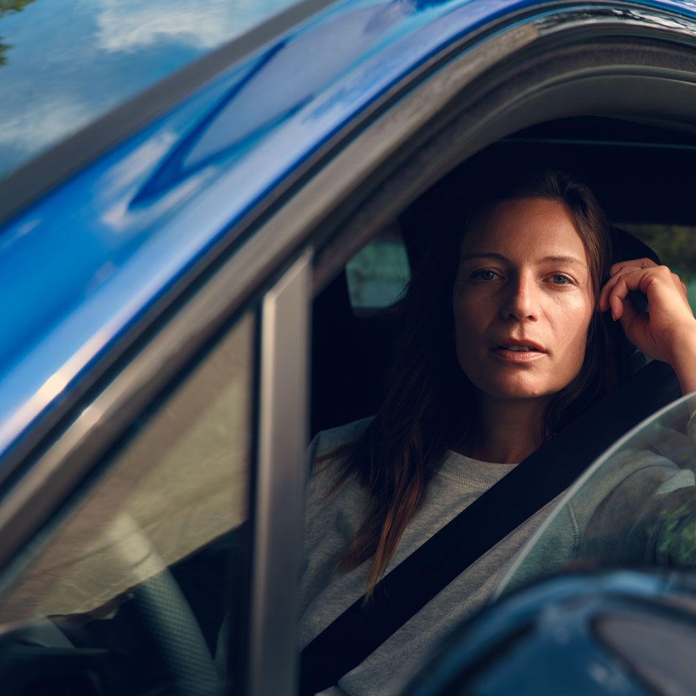 Eine Frau sitzt in einem VW Touareg R eHybrid und blickt in die Kamera