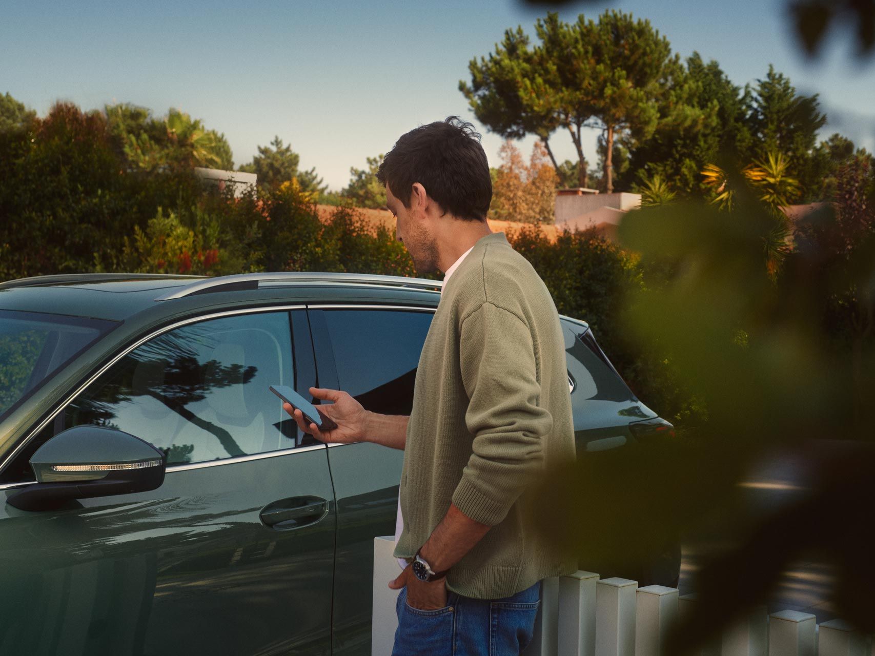 Mann bedient Park Assist des VW Tiguan auf seinem Smartphone