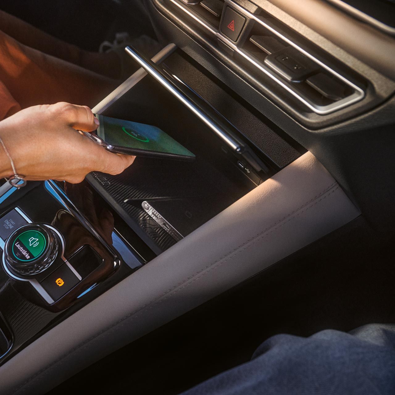 Person legt Smartphone in Ablage für Wireless Charging im VW Tiguan