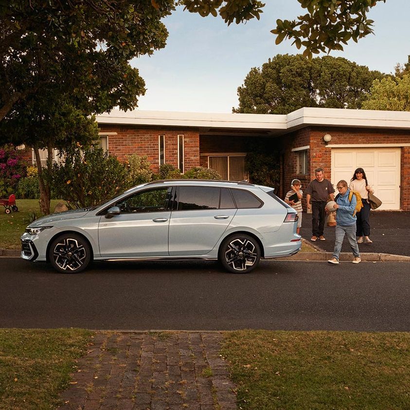 Seitenansicht eines VW Golf Variant in der Farbe Ice Blue Metallic geparkt vor Einfamilienhaus