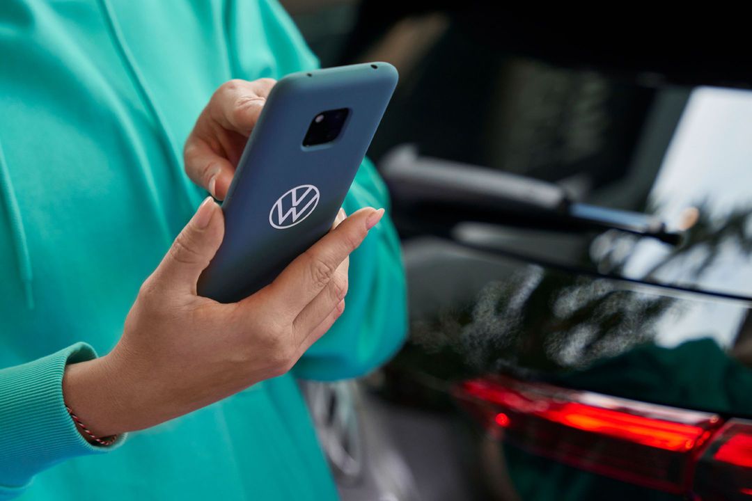 Eine Frau tippt in ihr Smartphone. Auf der blauen Schutzhülle ist das Volkswagen Logo abgebildet.