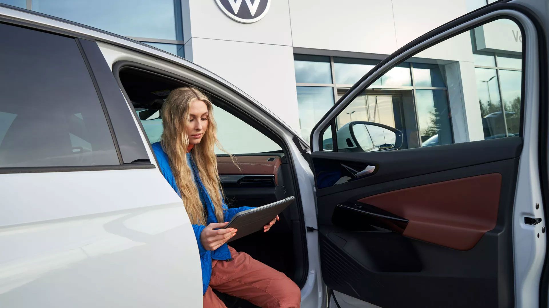 Eine Frau sitzt bei geöffneter Autotüre in einem VW ID.