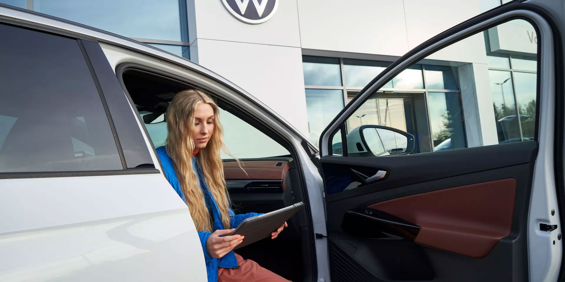 Eine Frau sitzt bei geöffneter Autotüre in einem VW ID.