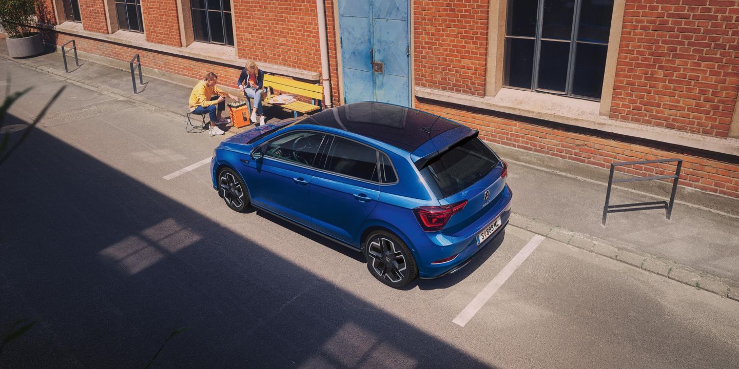 Pärchen spielt Schach und sitzt seitlich vor einem blauen VW Polo R-Line