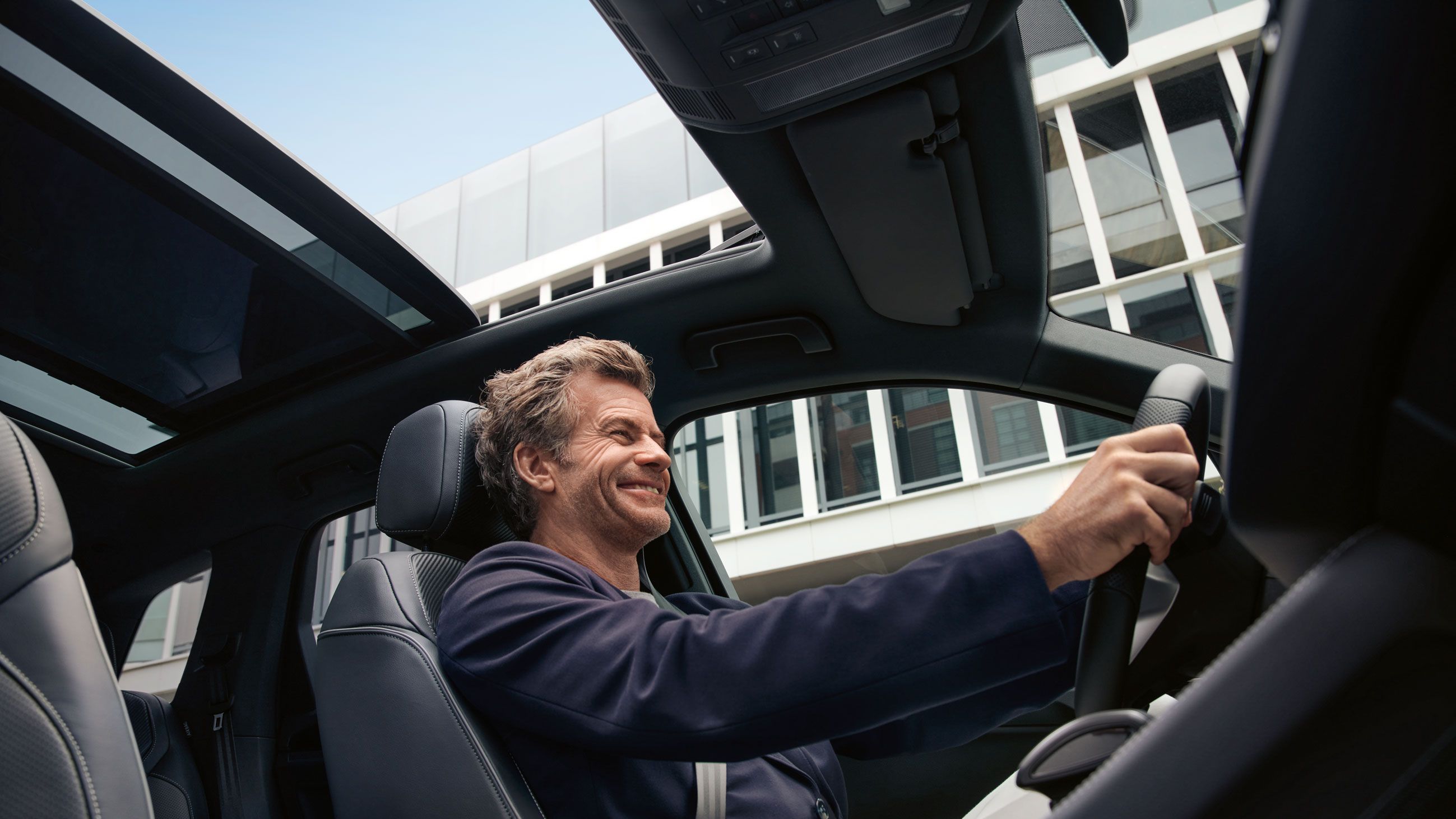 Blick durch das Panoramadach des VW Touareg, ein Mann sitzt am Steuer