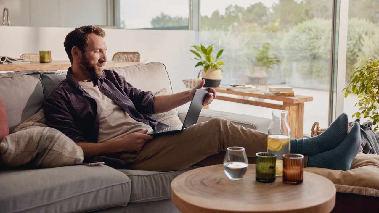 Mann sitzt zu Hause und schaut auf ein Tablet