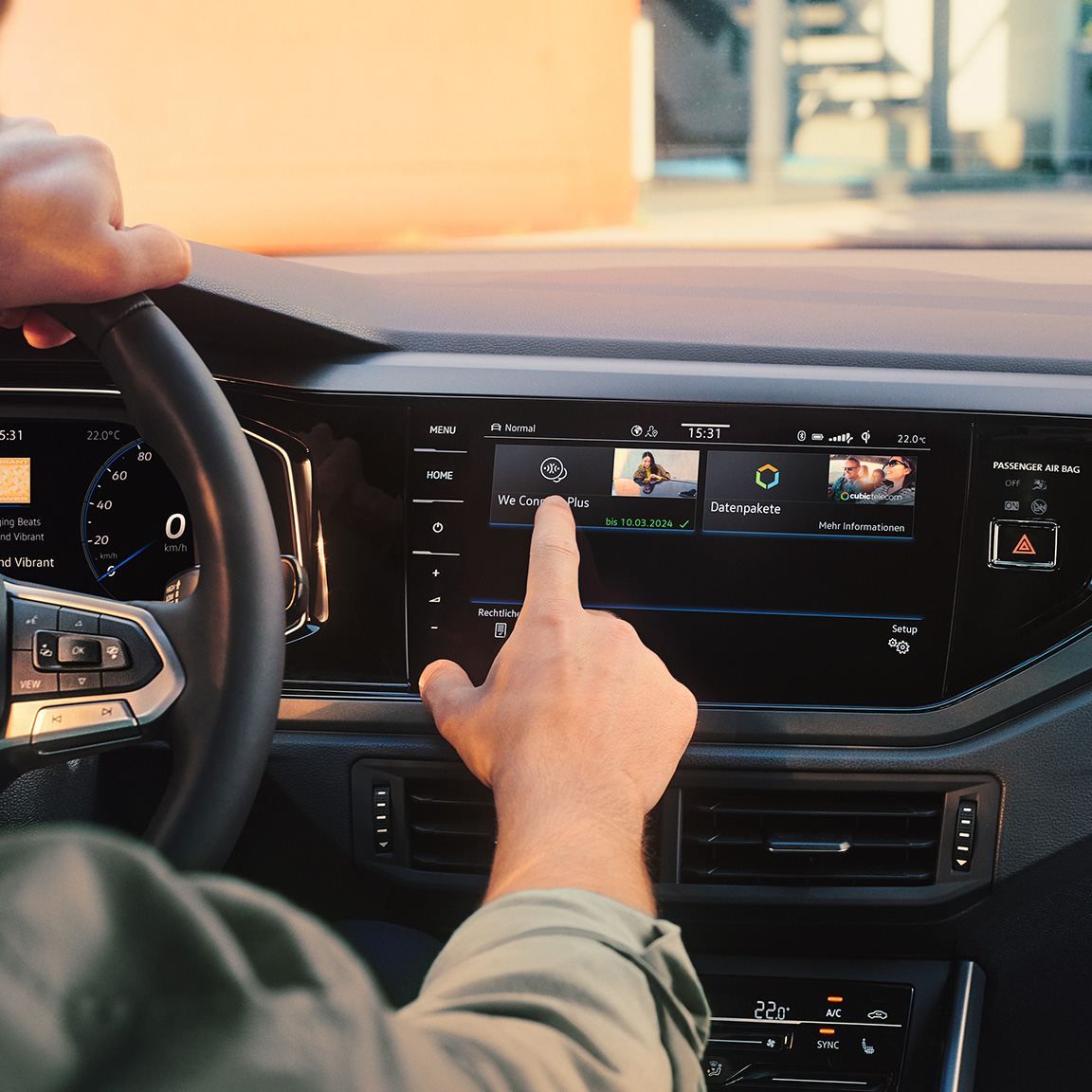 Blick auf das Display im VW Polo mit We Upgrade Funktionen. Ein Mann sitzt am Steuer und bedient das Display. 