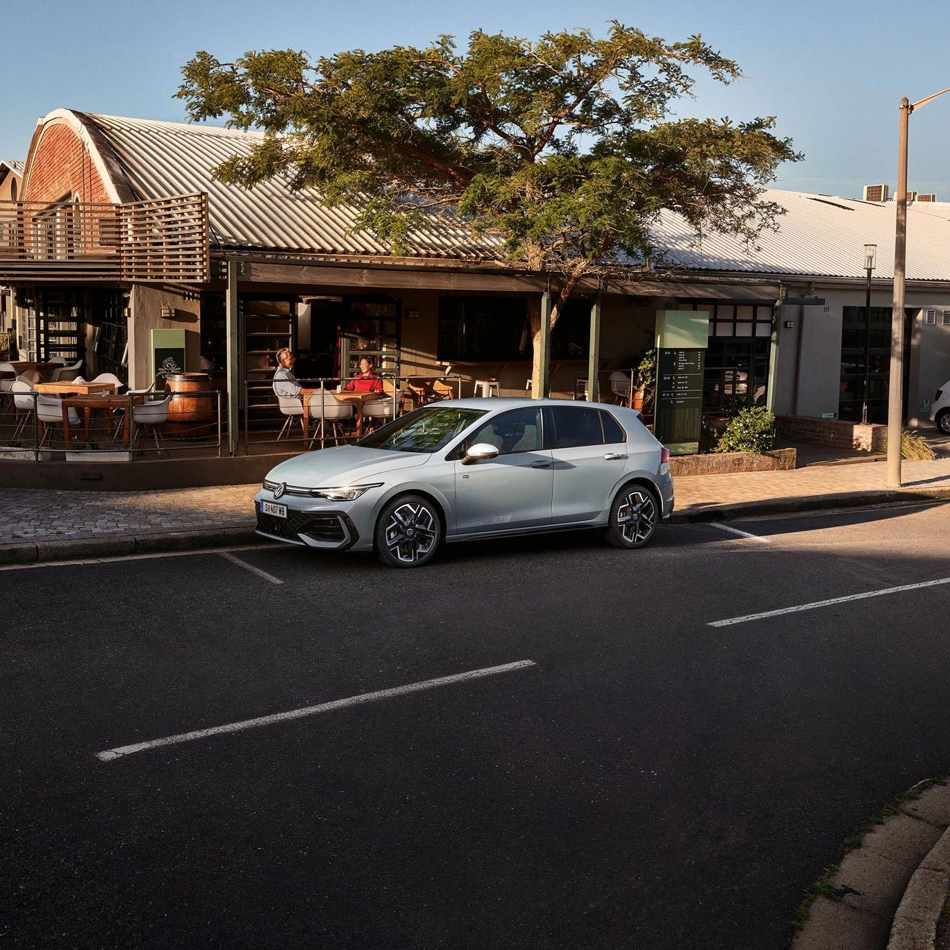 Der neue Golf GTE parkt an einem Straßenrand neben einem Café.