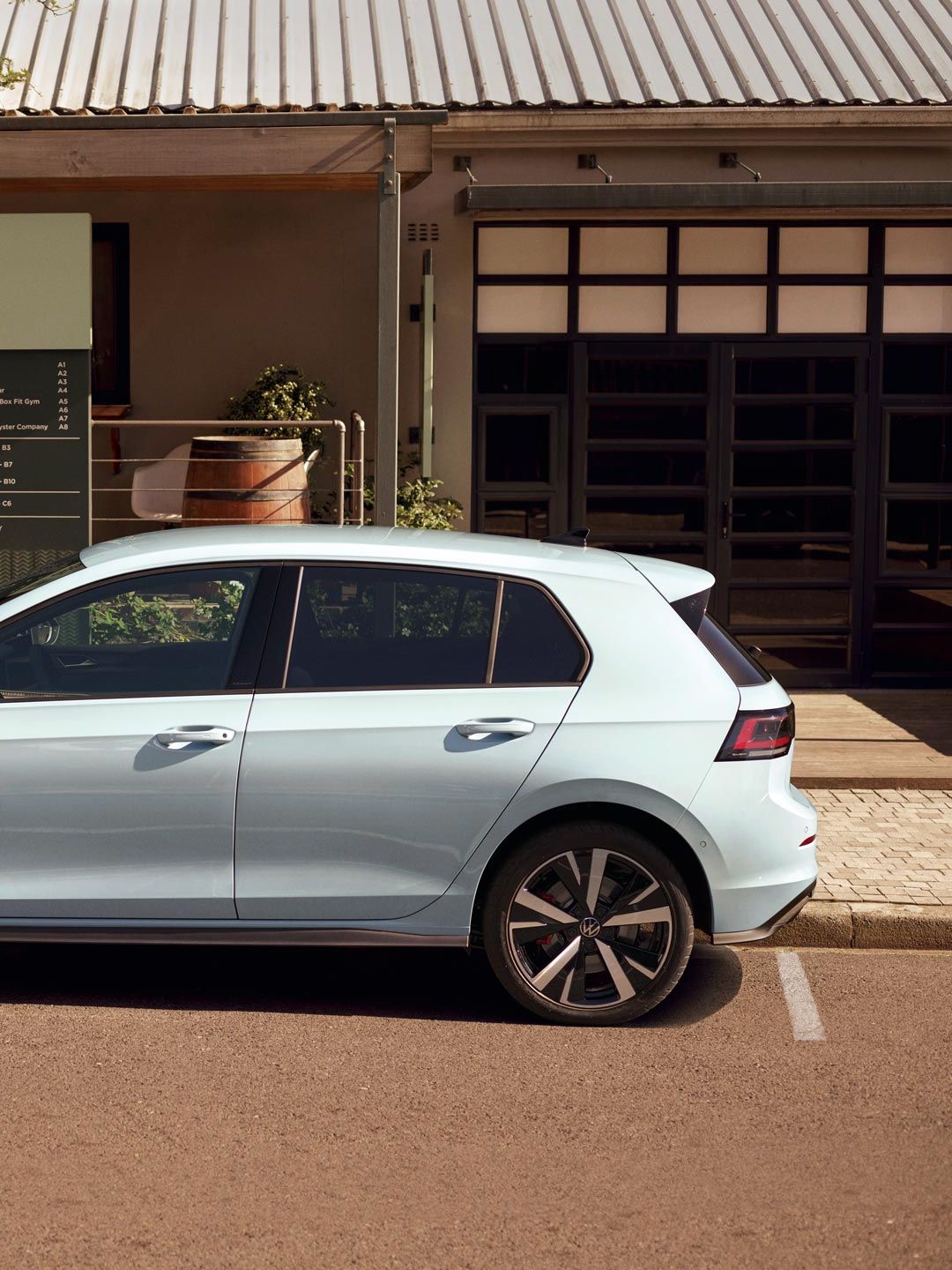 Seitenansicht eines VW Golf GTE in der Farbe Crystal Ice Blue der gerade an einer öffentlichen Ladestation geladen wird