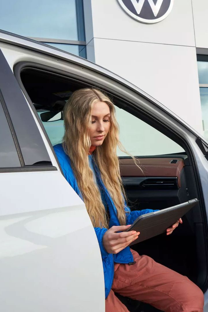 Eine Frau sitzt bei geöffneter Autotüre in einem VW ID.