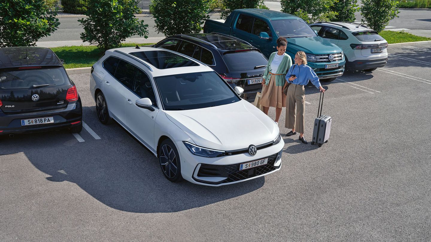 Zwei Frauen stehen auf einem Parkplatz neben einem weißen VW Passat B9