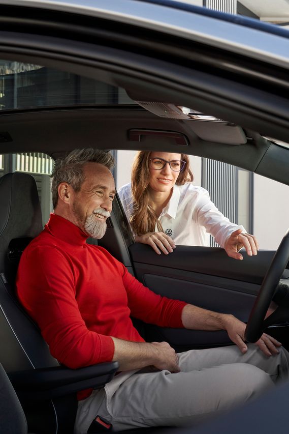 Ein Mann sitzt am Steuer eines Volkswagen und lächelt