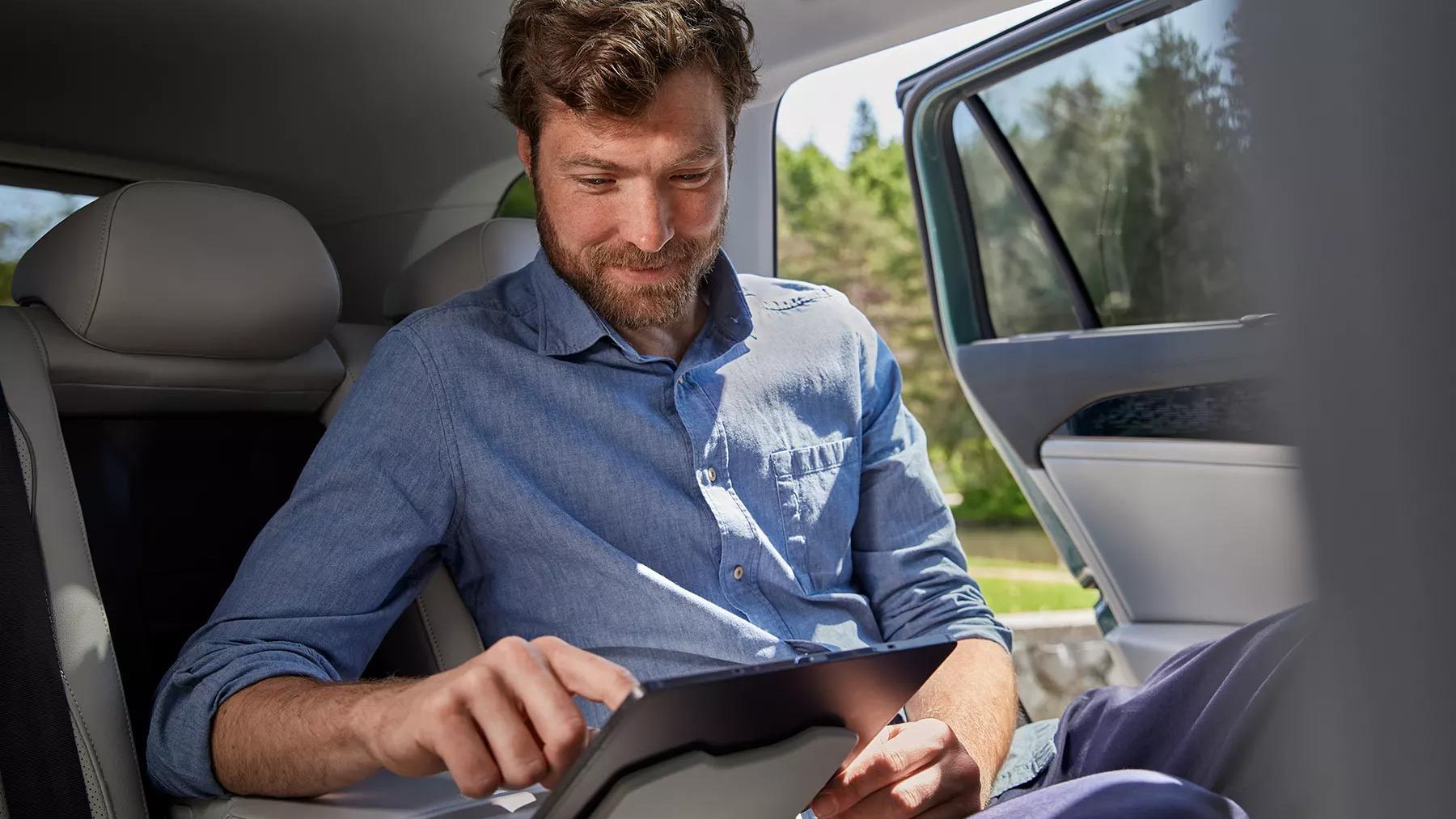 Mann sitzt auf Rückbank im VW Passat und bedient Tablet das in der Halterung befestigt ist