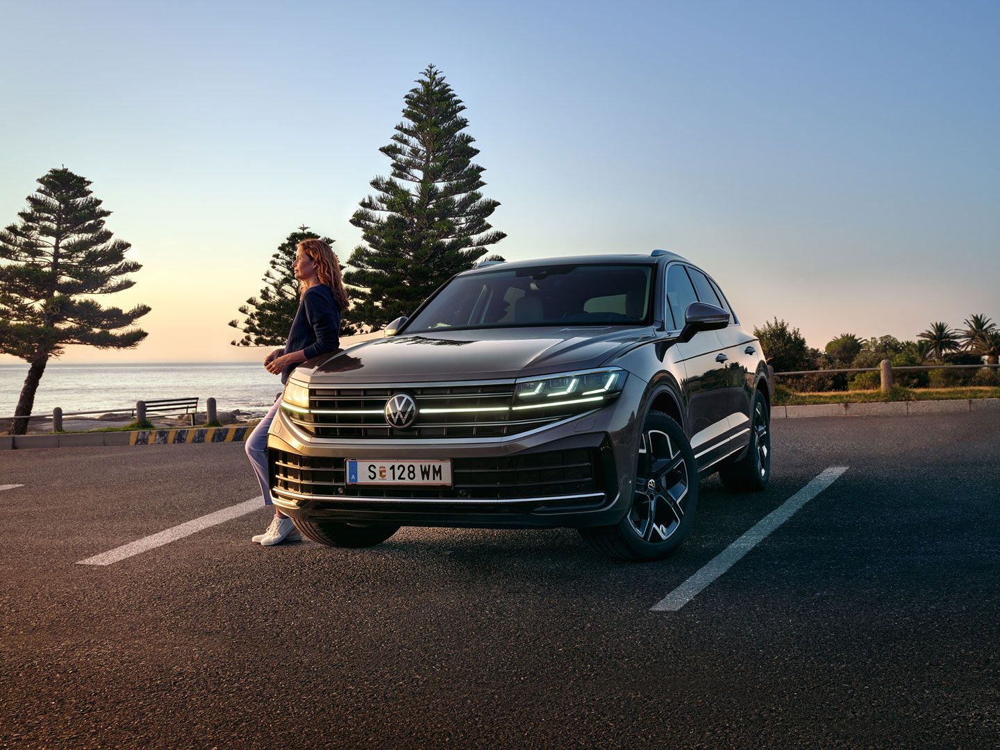 Ein VW Touareg Elegance in der Dämmerung am Meer mit eingeschalteten HD-Matrix-Scheinwerfern. 