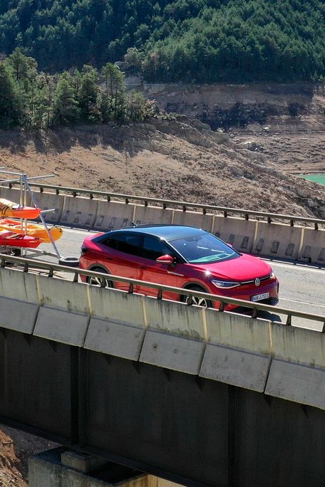 Ein roter ID.5 GTX fährt mit einem Anhänger über eine Brücke