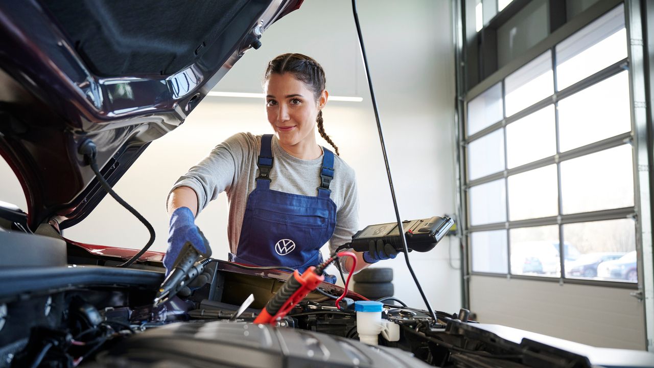 Eine Volkswagen Mechanikerin überprüft die Batterie eines Volkswagen