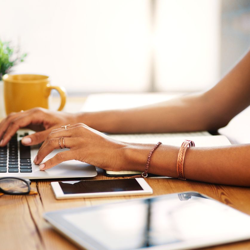 Frau sitzt am Tisch vor Laptop