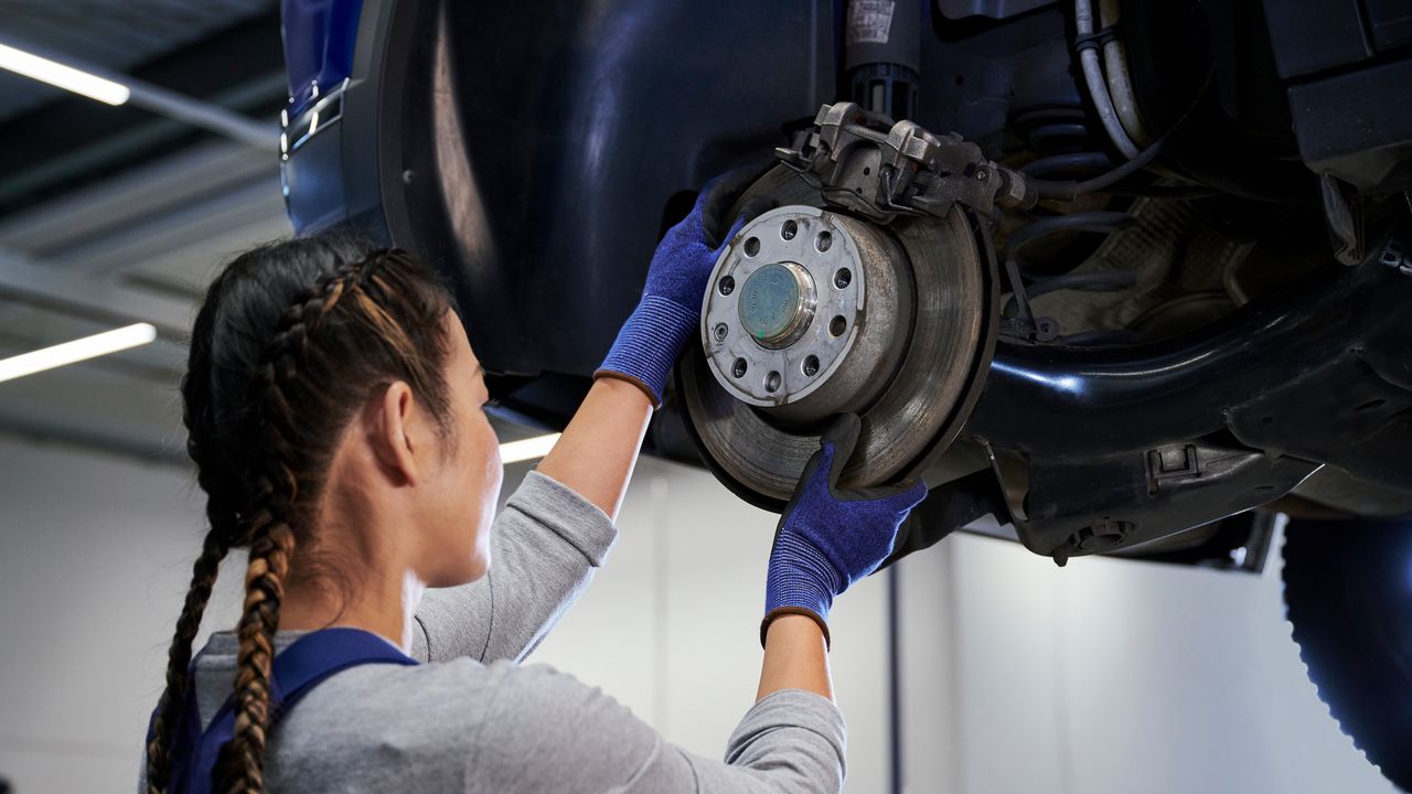 VW Mechanikerin beim Bremsenservice