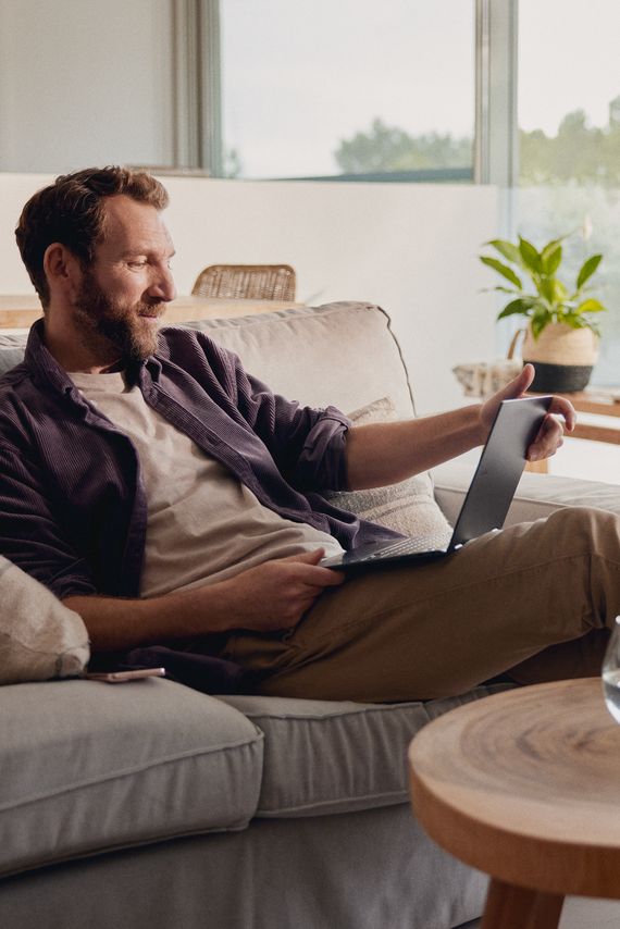 Mann sitzt zu Hause und schaut auf ein Tablet