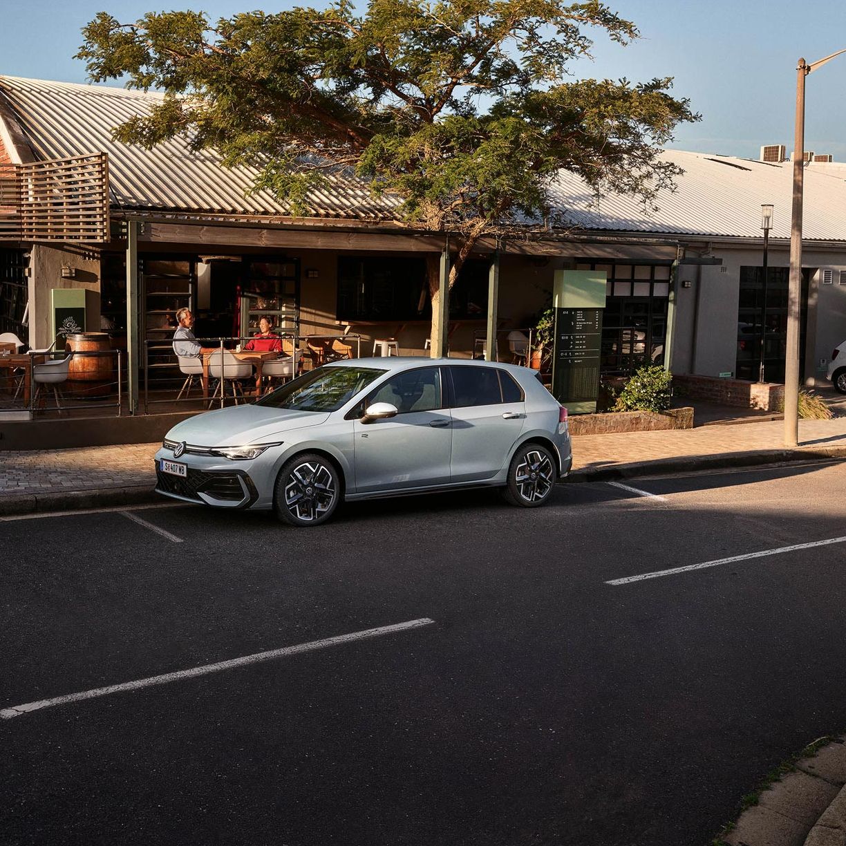 Der neue Golf GTE parkt an einem Straßenrand neben einem Café.