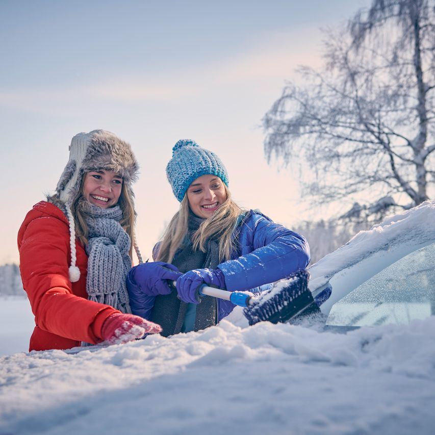 Zwei Frauen befreien die Windschutzscheibe vom Schnee