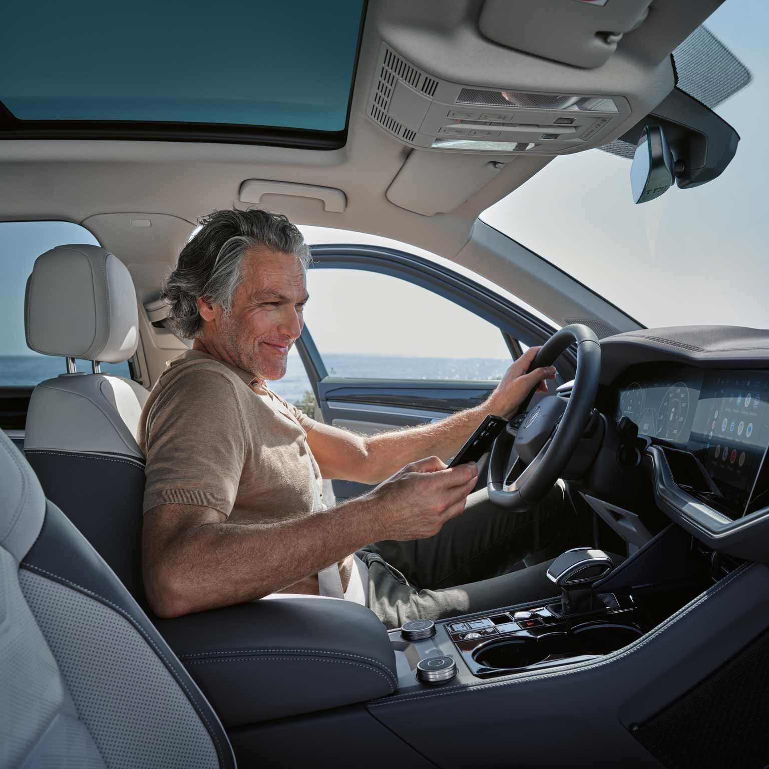 Mann sitz mit seinem Handy in eine Touareg eHybrid