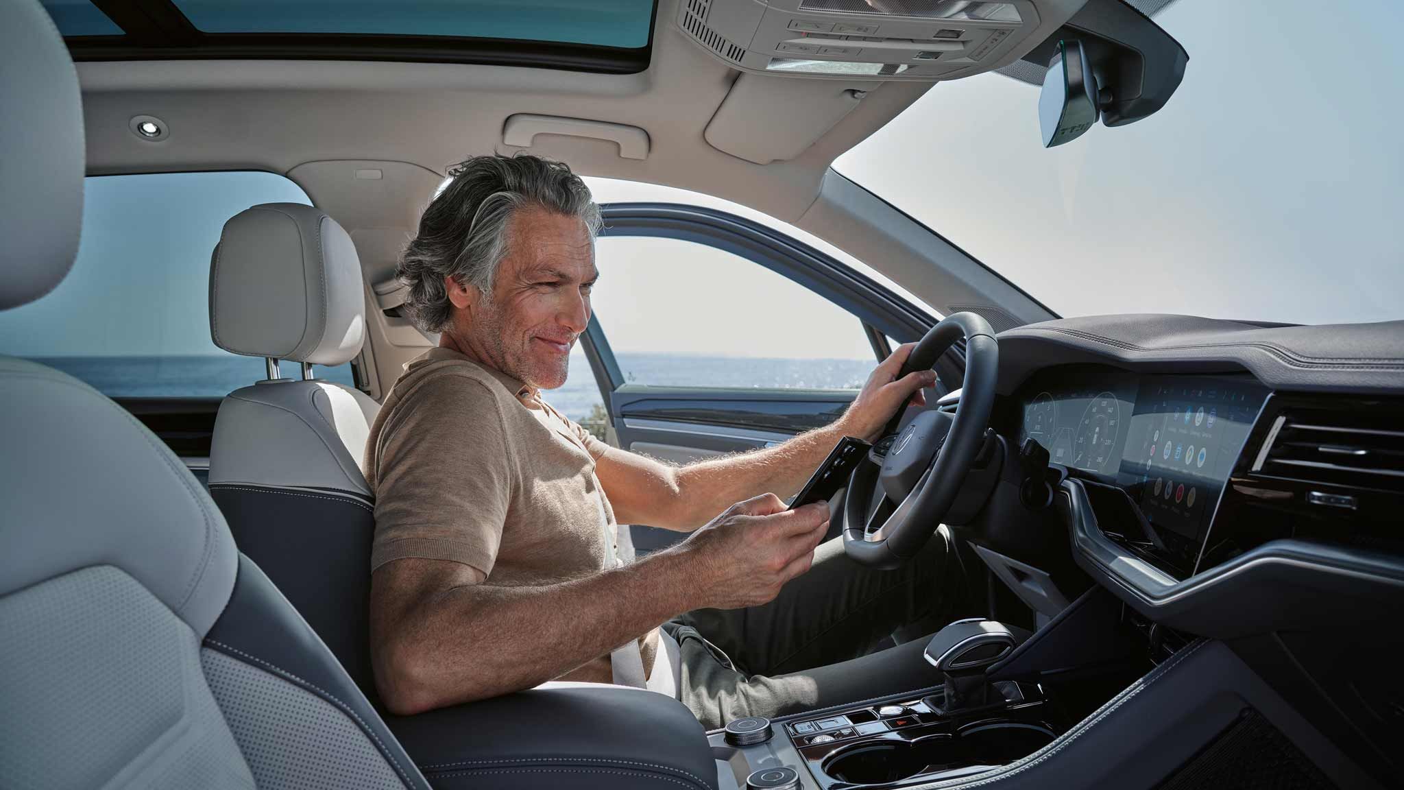 Mann sitz mit seinem Handy in eine Touareg eHybrid