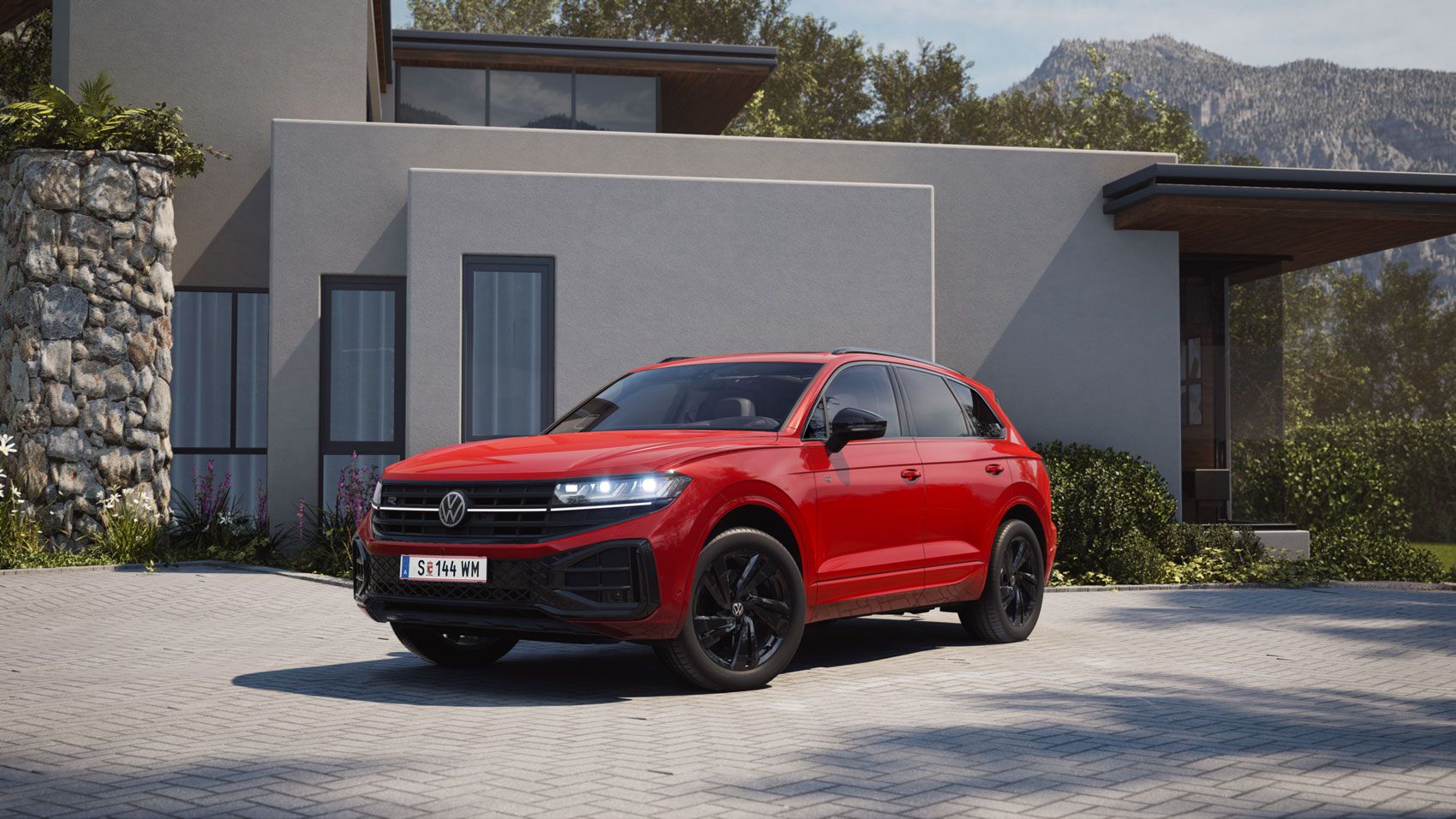 Blick von der Front über die Seite auf einen roten VW Touareg mit R-Line „Exterieur Black Style“-Elementen.