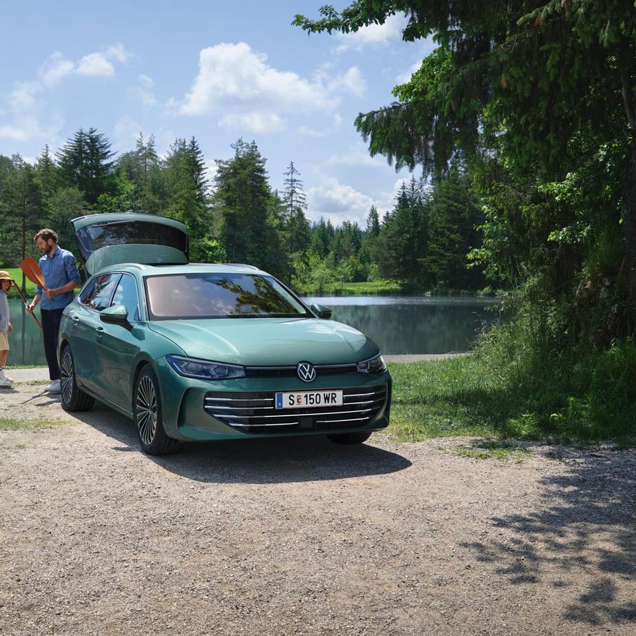 Der neue VW Passat Elegance in Maripositgrün Metallic parkt an einem Badesee mit geöffnetem Kofferraum. Ein Mann verteilt Freitzeitspielzeug an zwei Kinder.