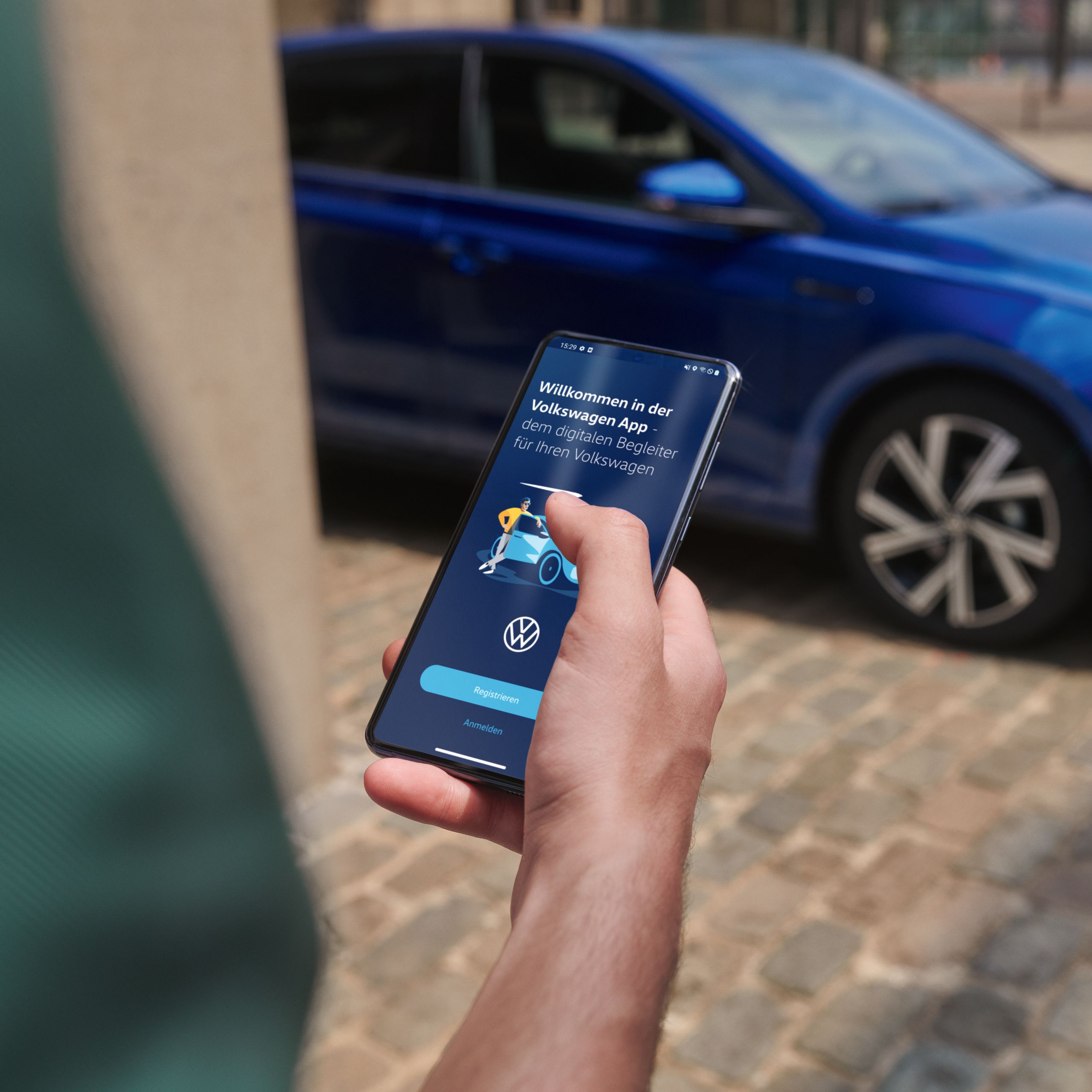 Person nutzt die Volkswagen App auf dem Smartphone, im Hintergrund ein blauer Polo R-Line