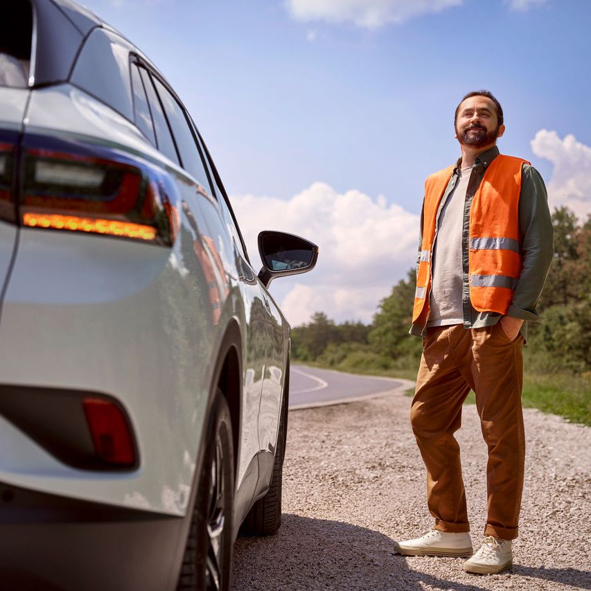  Mann steht vor seinem Volkswagen in einer Warnweste