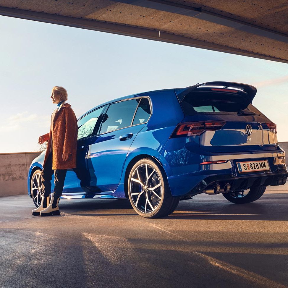 Frau lehnt sich an blauen VW Golf R