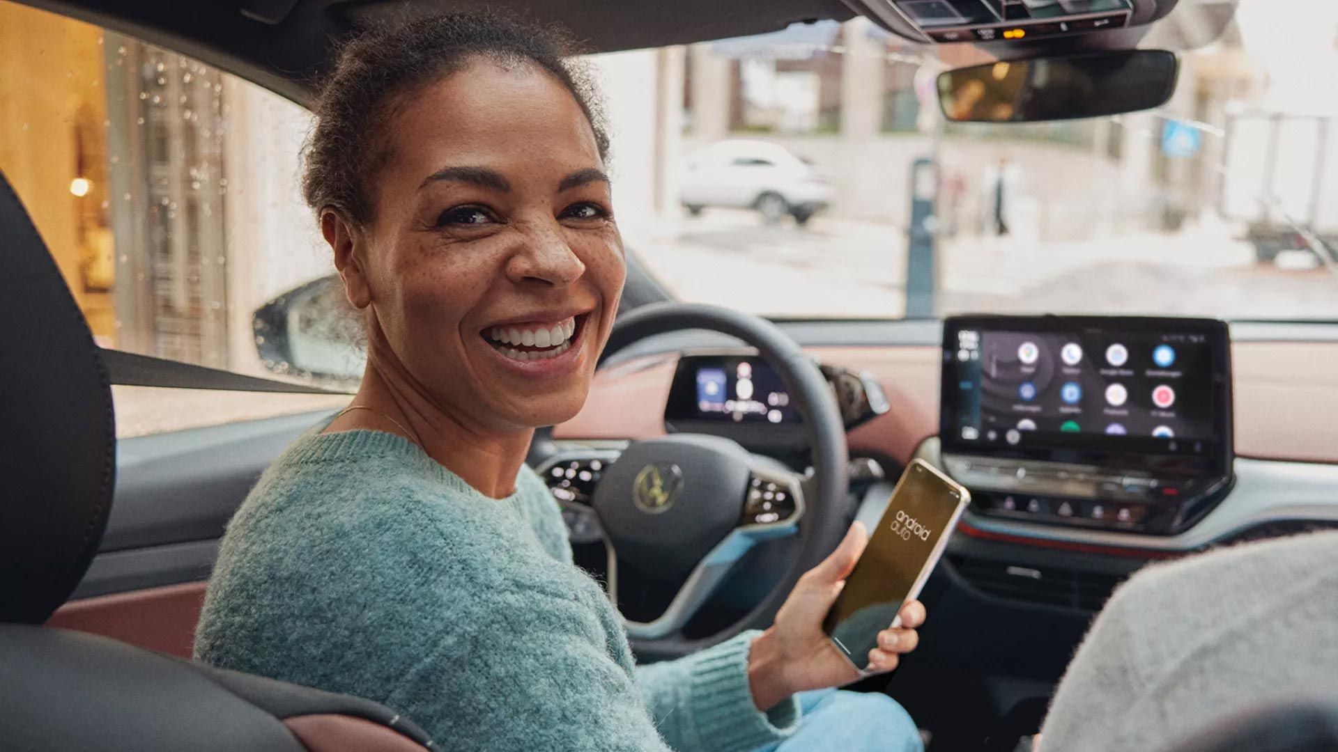 Frau lächelnd mit Smartphone in der Hand nutzt Android Auto im ID.