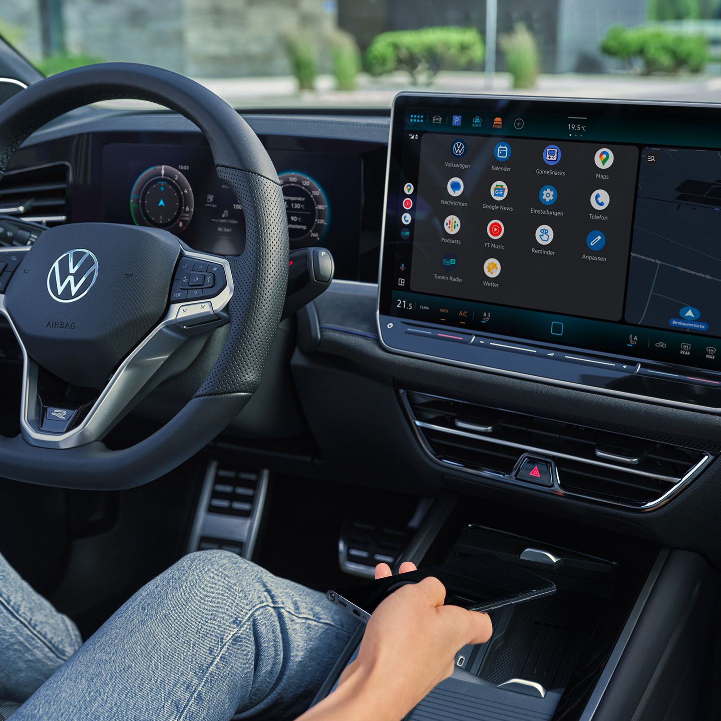 Detailansicht auf das Cockpit des VW Passast. Eine Person auf dem Fahrersitz hält ein Smartphone in der Hand.