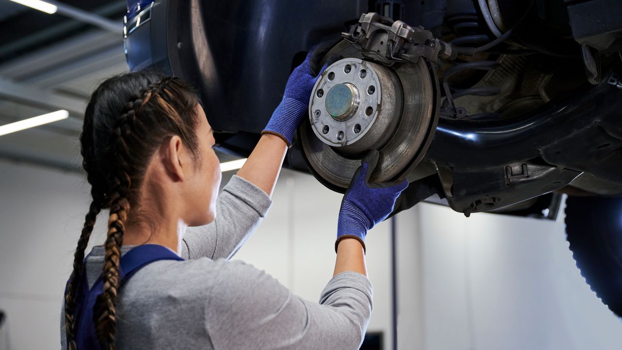 VW Mechanikerin beim Bremsenservice