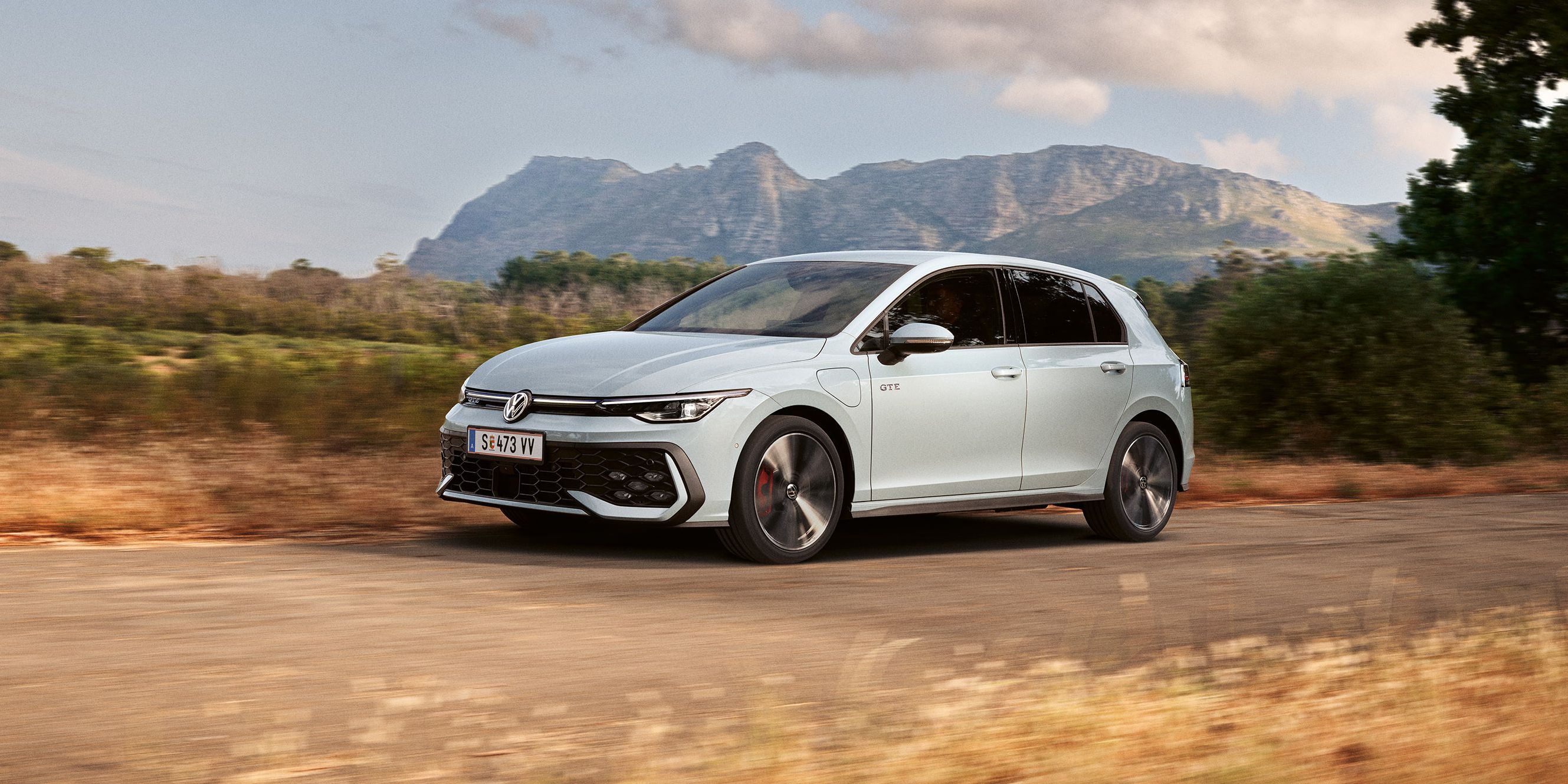 Der VW Golf GTE fährt auf einer Landstraße, im Hintergrund sieht man Berge