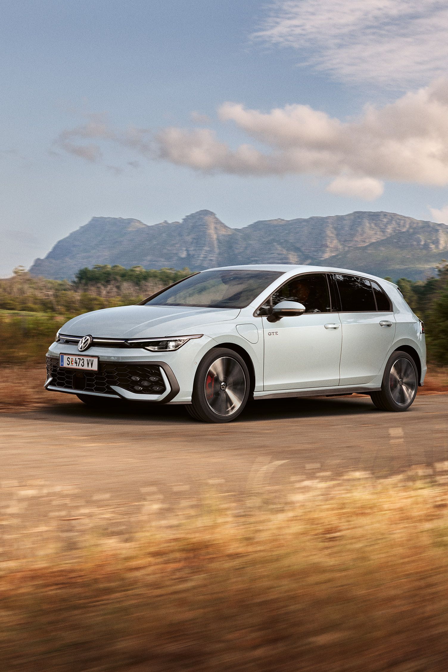 Der VW Golf GTE fährt auf einer Landstraße, im Hintergrund sieht man Berge