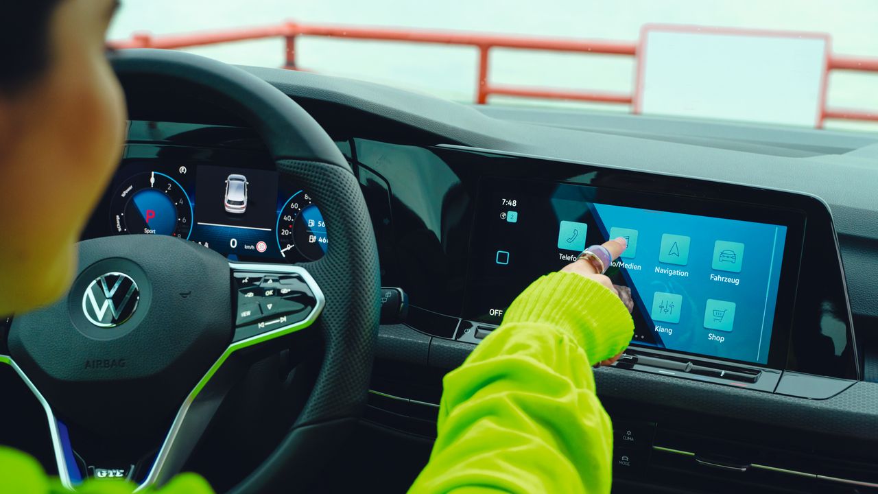 Frau bedient Cockpit Display im VW Golf GTE.