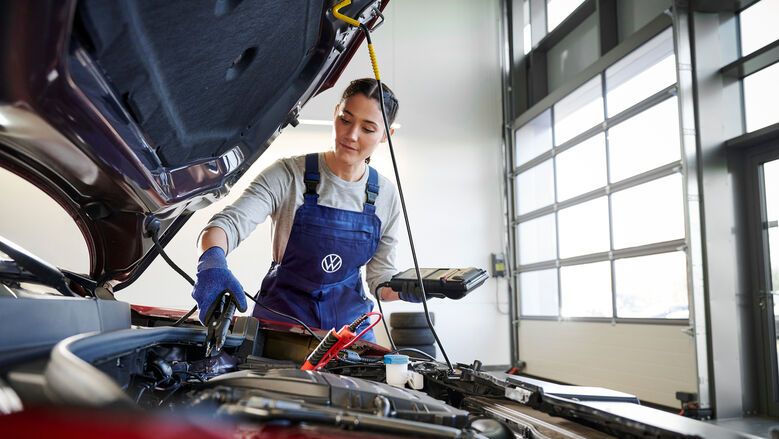 Volkswagen Service Technikerin vor geöffneter Motorhaube