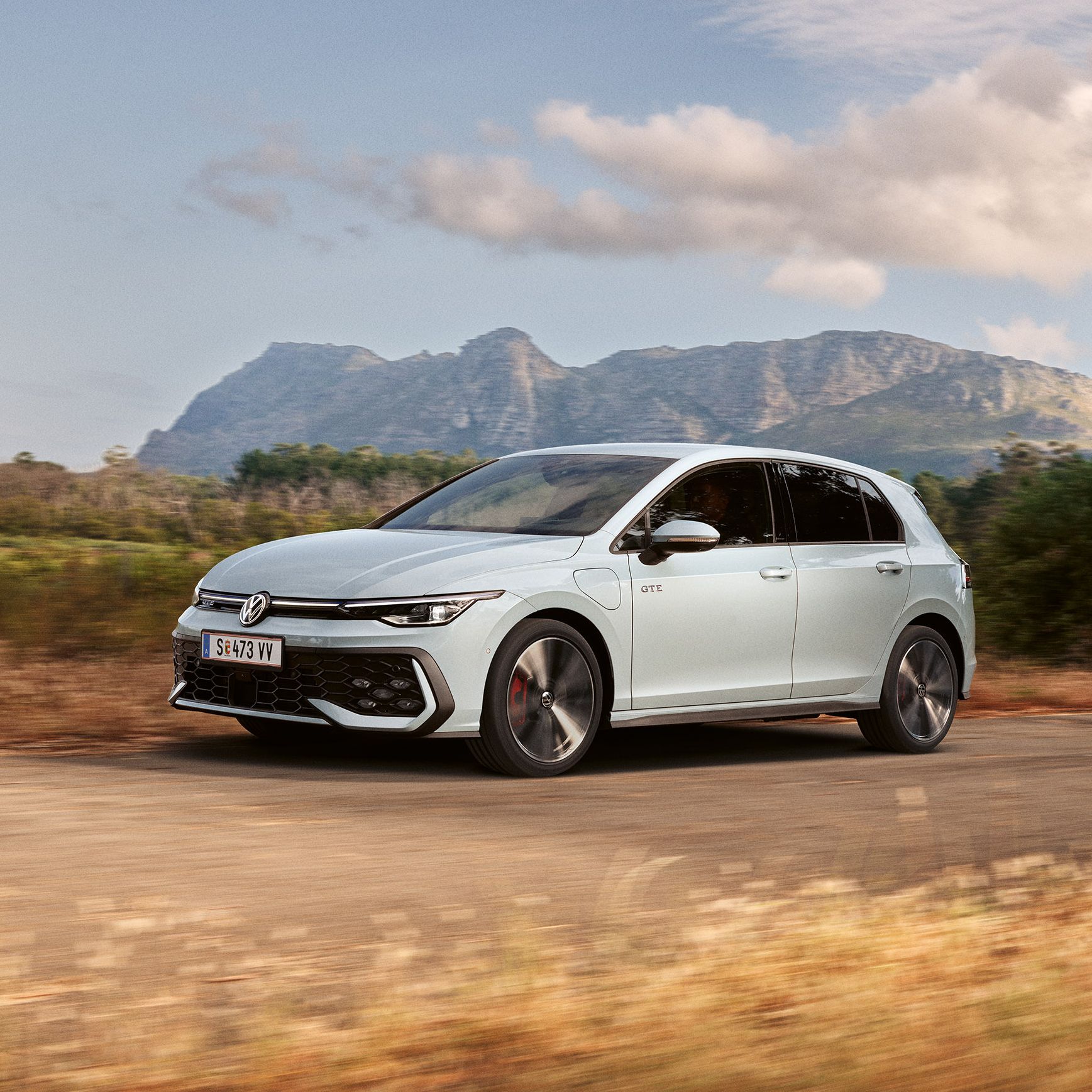 Der VW Golf GTE fährt auf einer Landstraße, im Hintergrund sieht man Berge