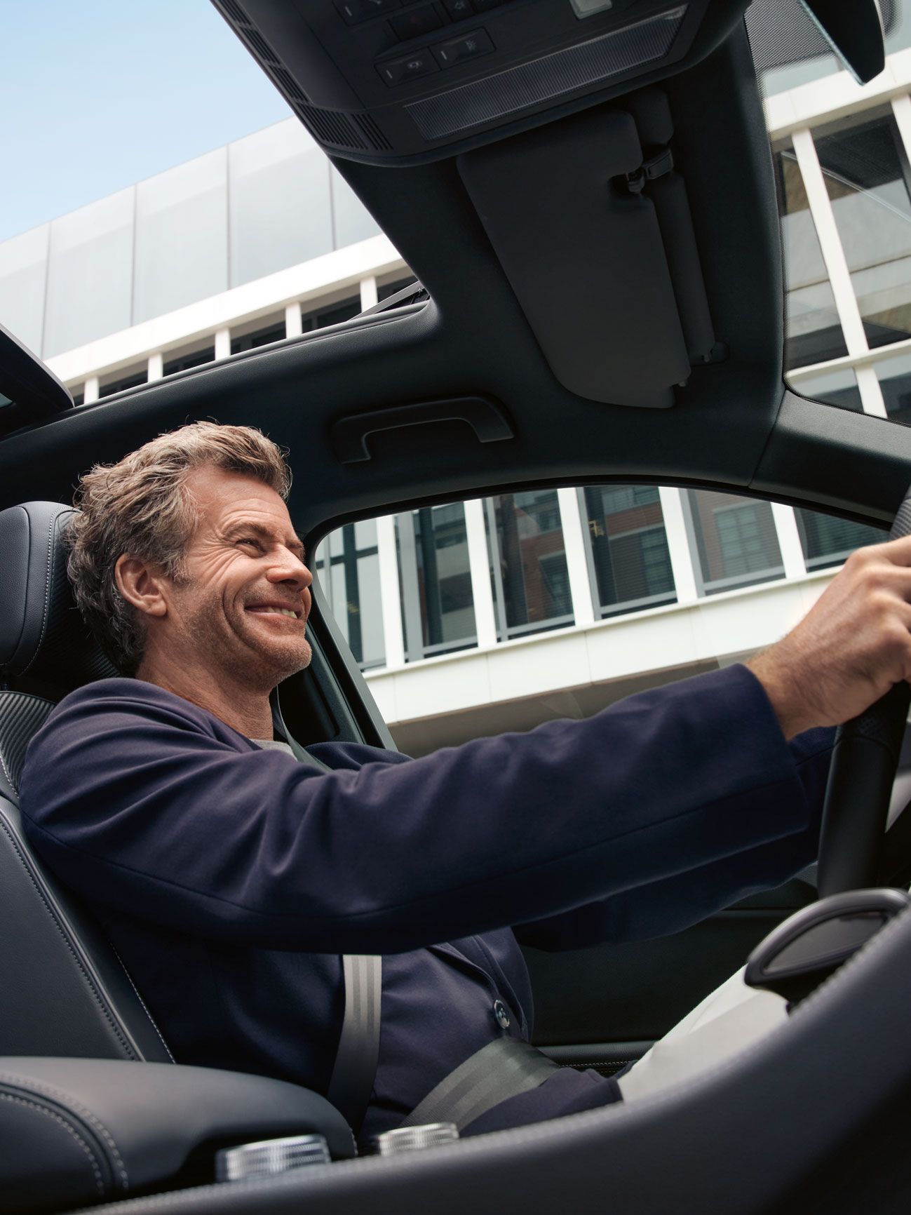 Blick durch das Panoramadach des VW Touareg, ein Mann sitzt am Steuer