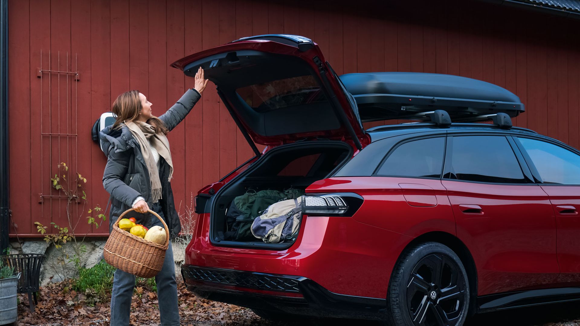 Eine Frau schließt die Heckklappe des VW ID.7 Tourer GTX per Knopfdruck