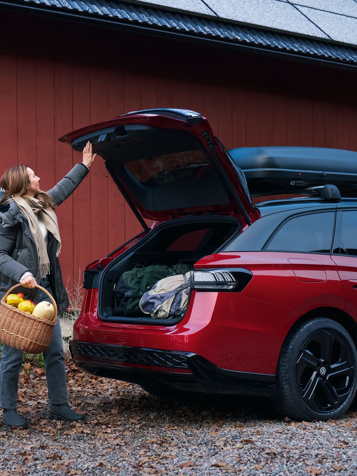 Eine Frau schließt die Heckklappe des VW ID.7 Tourer GTX per Knopfdruck