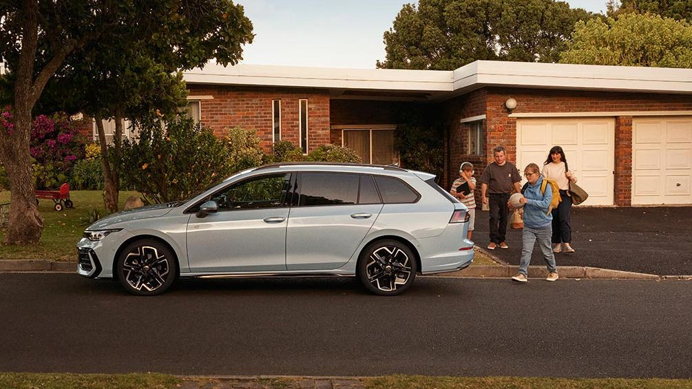 Seitenansicht eines VW Golf Variant in der Farbe Ice Blue Metallic geparkt vor Einfamilienhaus