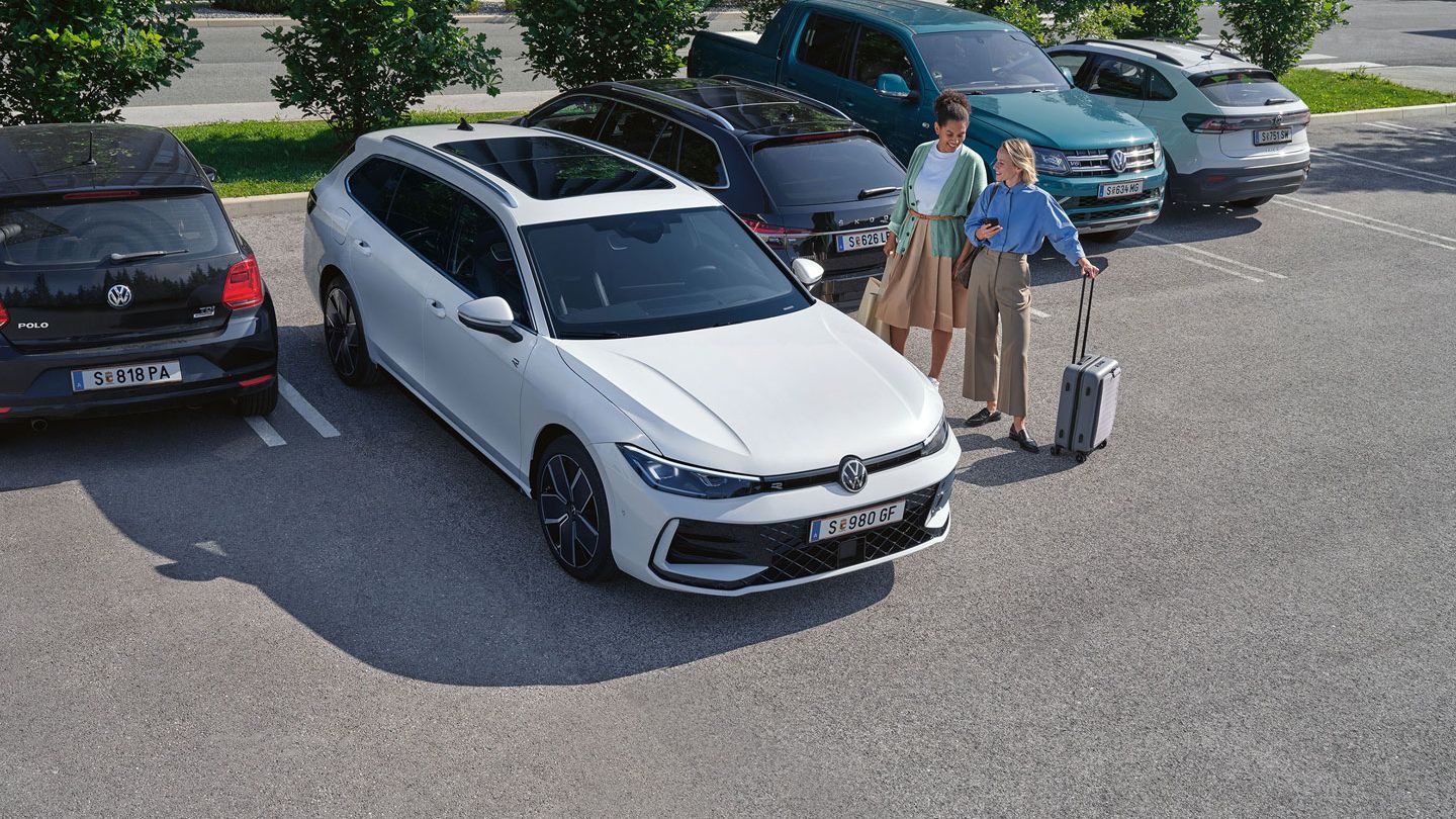 Zwei Frauen stehen auf einem Parkplatz neben einem weißen VW Passat B9