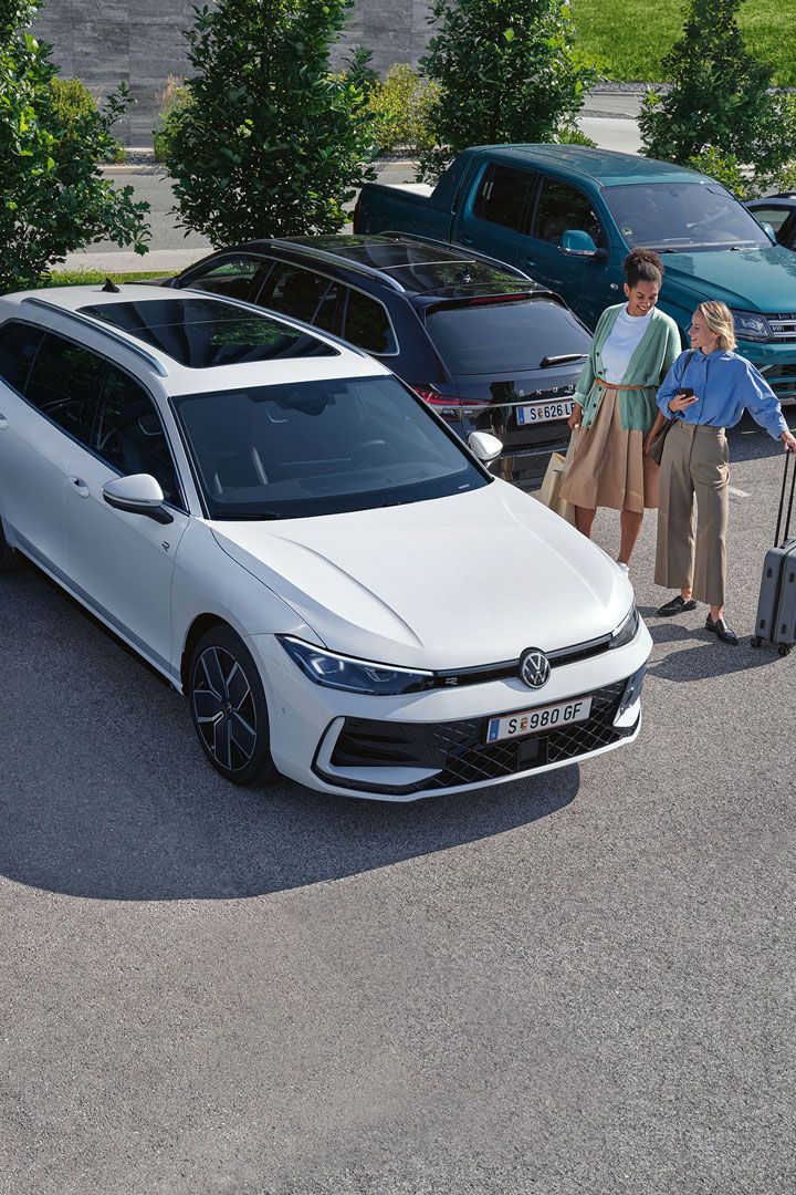 Zwei Frauen stehen auf einem Parkplatz neben einem weißen VW Passat B9