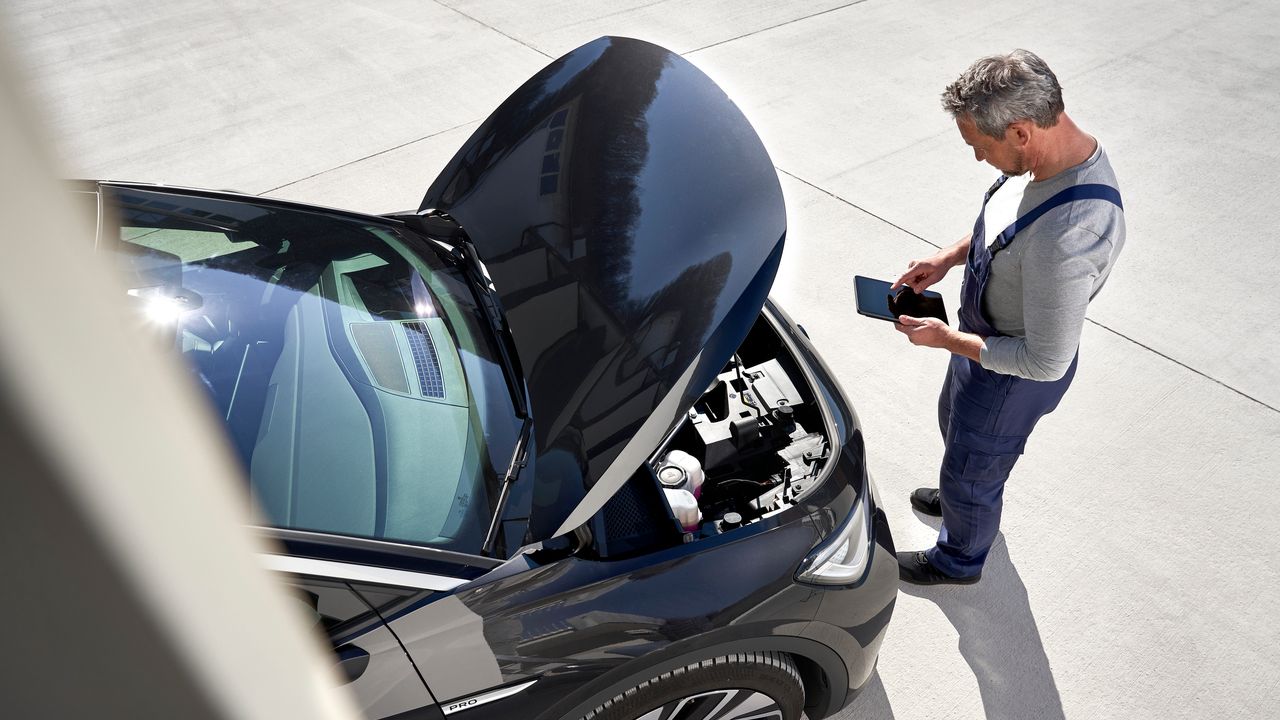 Volkswagen Service Techniker vor geöffneter Motorhaube