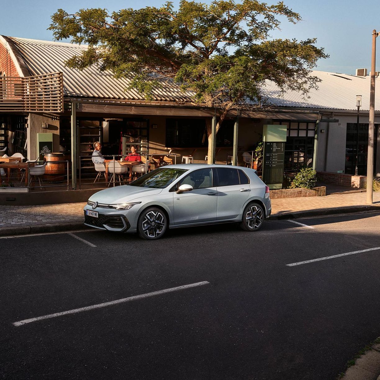 Der neue Golf GTE parkt an einem Straßenrand neben einem Café.