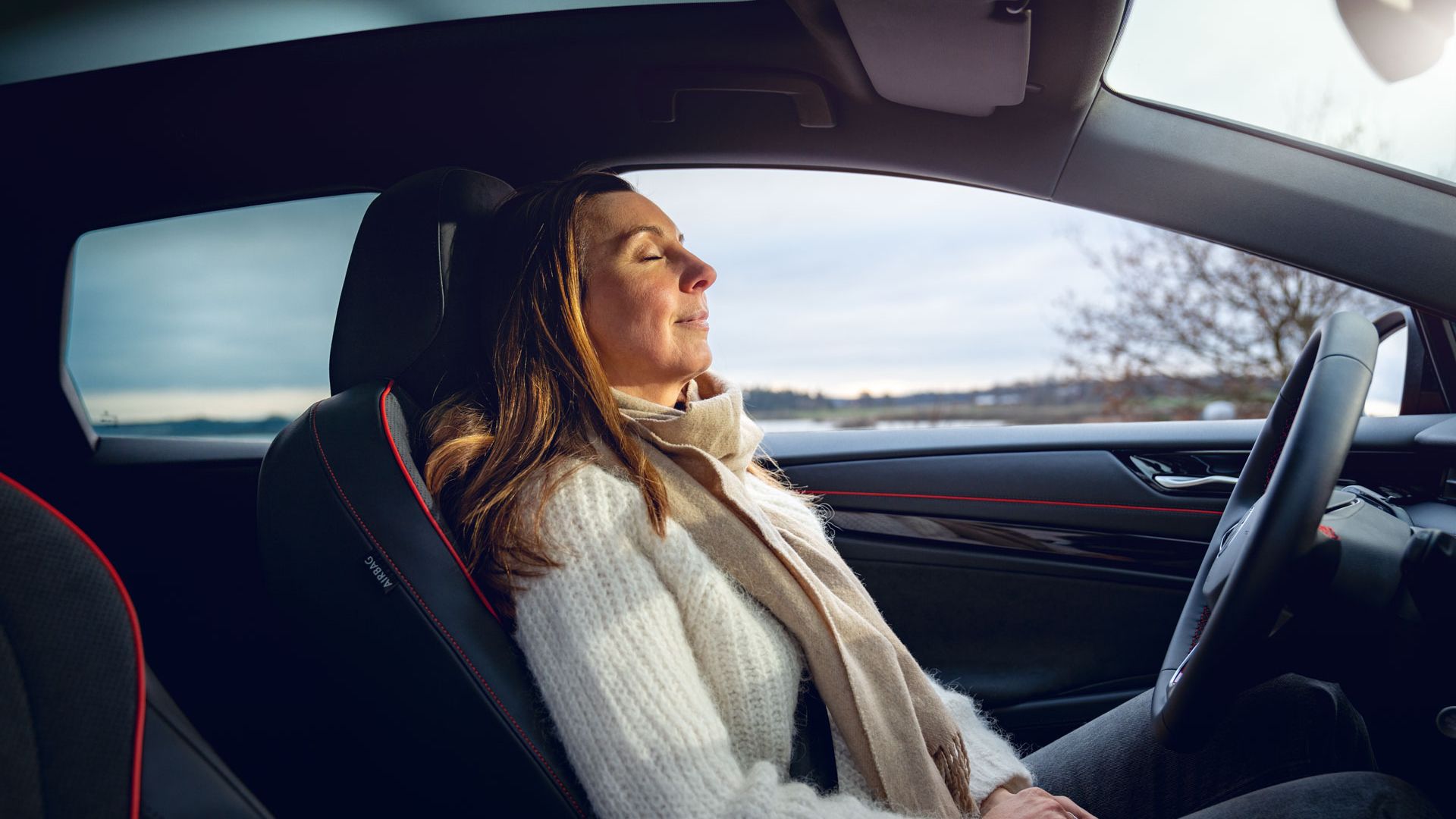 Eine Frau sitzt im geparkten VW ID.7 Tourer GTX und schließt die Augen